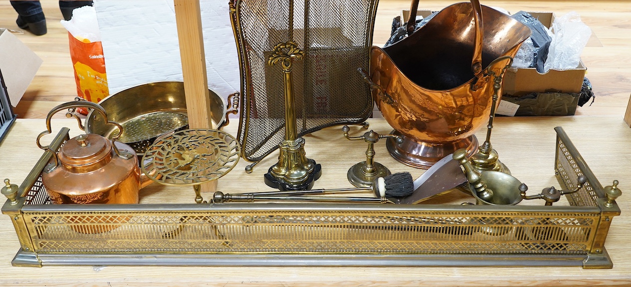 A Victorian brass fender, a fire screen, implements, fire dogs, a bronze pestle and mortar, a copper helmet coal scuttle, etc. Condition - fair